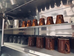 Uma máquina de café com diversas opções de preparo e uma seleção de xícaras de café expostas.
