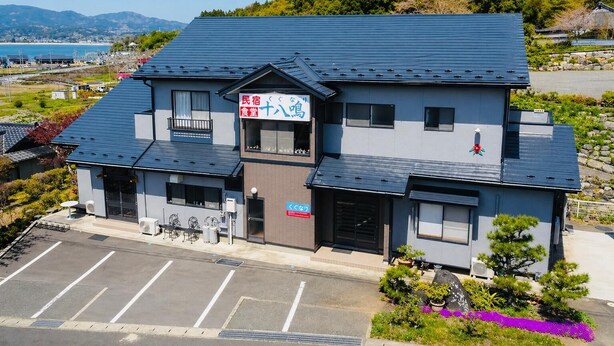 Un edificio de dos pisos con techo azul, un letrero de restaurante y un estacionamiento.