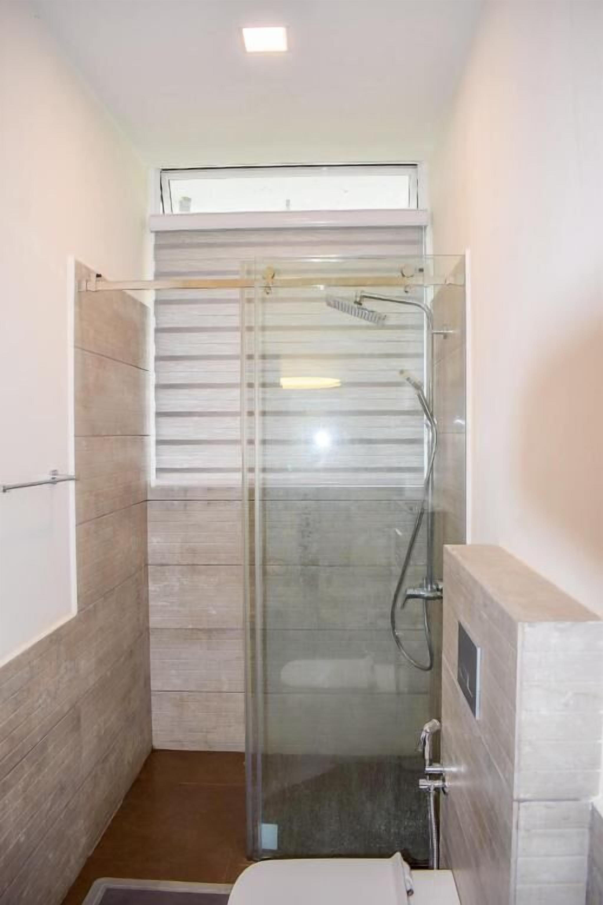 A modern bathroom with a glass-enclosed shower, a toilet, and a sink.
