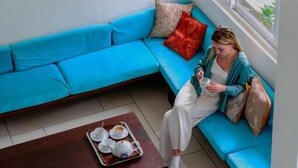 Une pièce avec un canapé bleu, un banc en bois et un plateau contenant des tasses et des soucoupes.