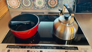 A kitchen with a red pot on an induction cooktop, a stainless steel kettle, and a tiled backsplash. - Wood Retreat (Miyazaki)