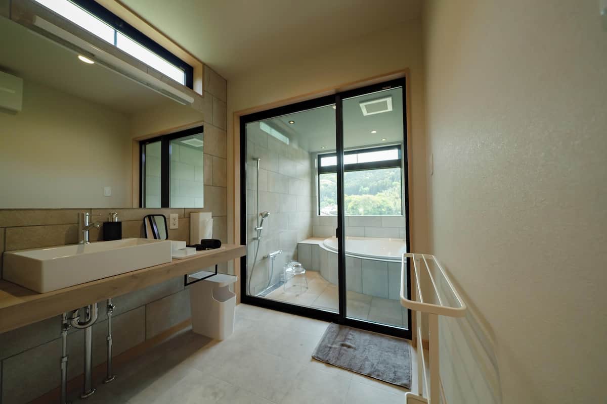 Un baño moderno con un espejo grande, un lavamanos, una ducha y una bañera.