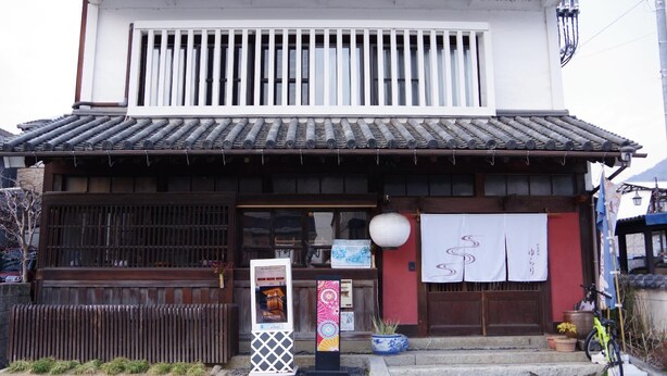 A traditional Japanese building with a tiled roof, wooden sliding doors, and a small entrance with steps.