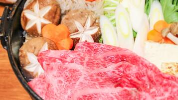 A bowl of food with various ingredients including meat, vegetables, and noodles.