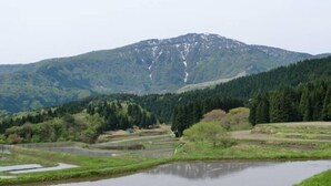 Paisaje montañoso con un río, zona boscosa y un pequeño edificio.