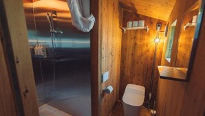 Ein Badezimmer einer Holzhütte mit Dusche, Toilette und Spiegel.