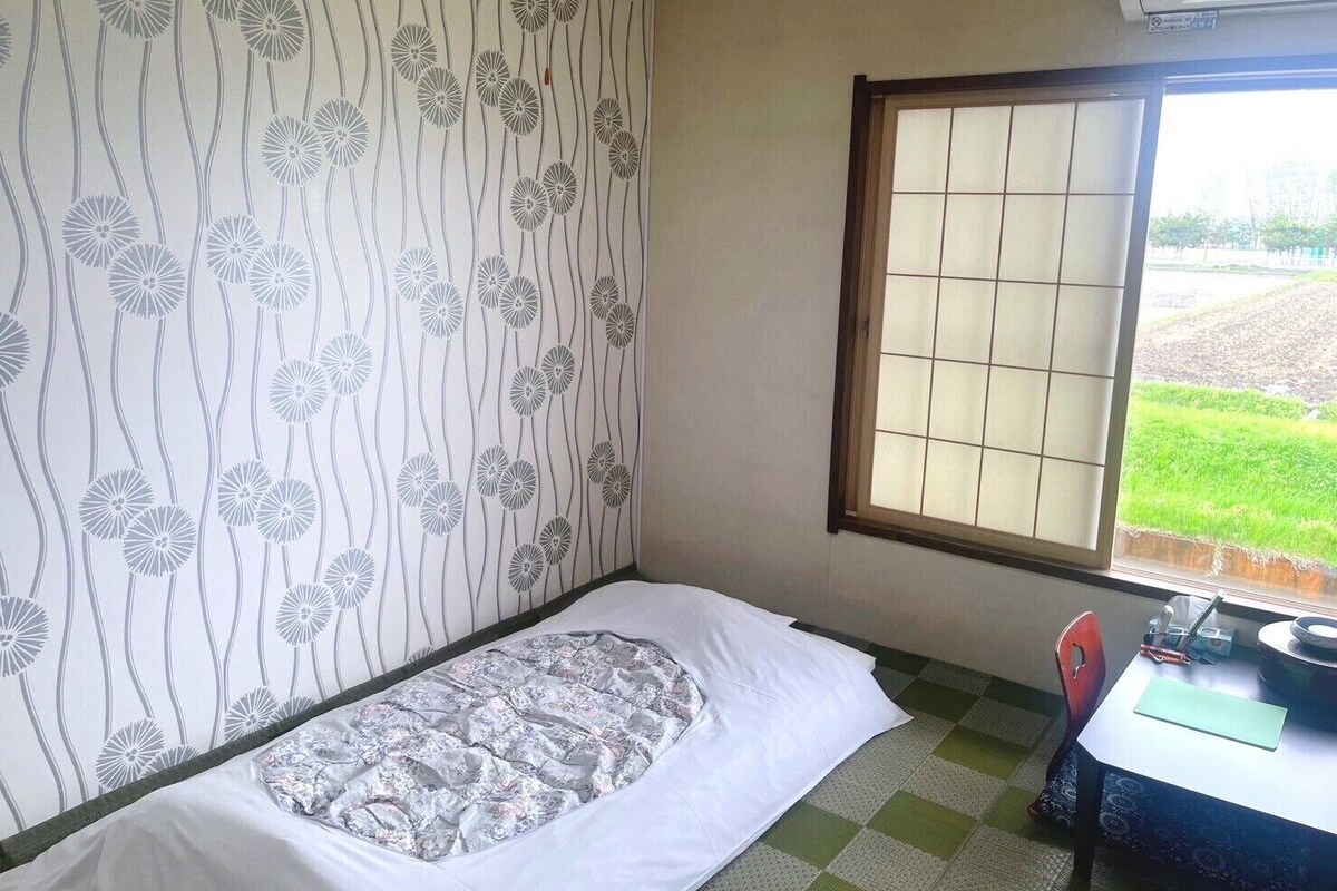 A small room with a bed, a window, and a desk with a chair.
