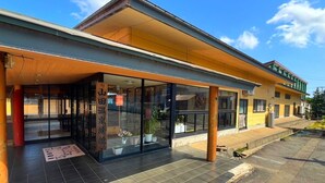 A building with a covered entrance, large windows, and a tiled ground.