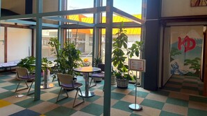 A cafe with a checkered floor, metal-framed tables, chairs, and potted plants.
