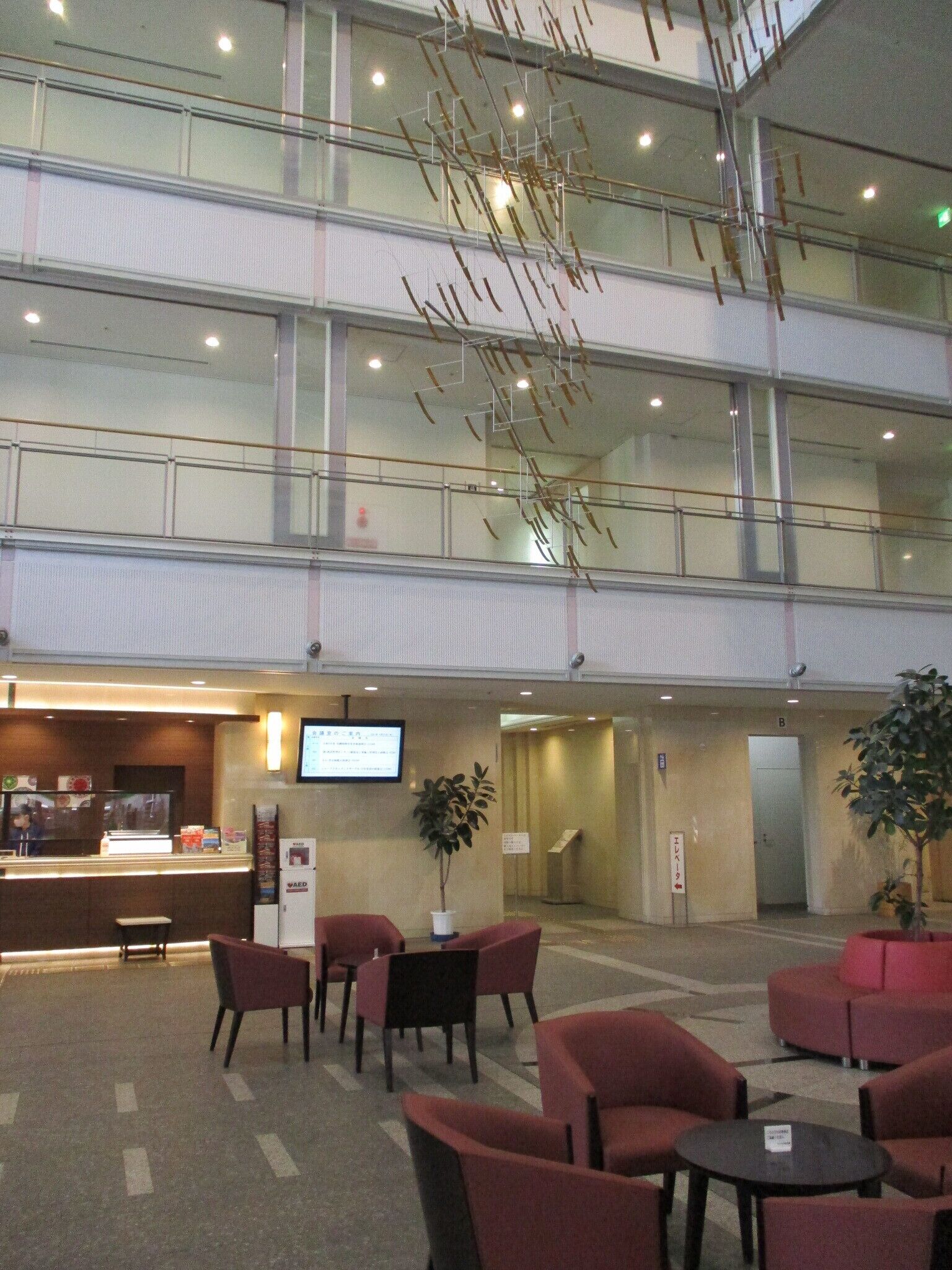 A hotel lobby with a reception desk, seating area, and a staircase.