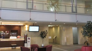 A hotel lobby with a reception desk, seating area, and a staircase. - Natural Hotspring Hotel Jichikaikan (Kagoshima)