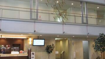 A hotel lobby with a reception desk, seating area, and a staircase.
