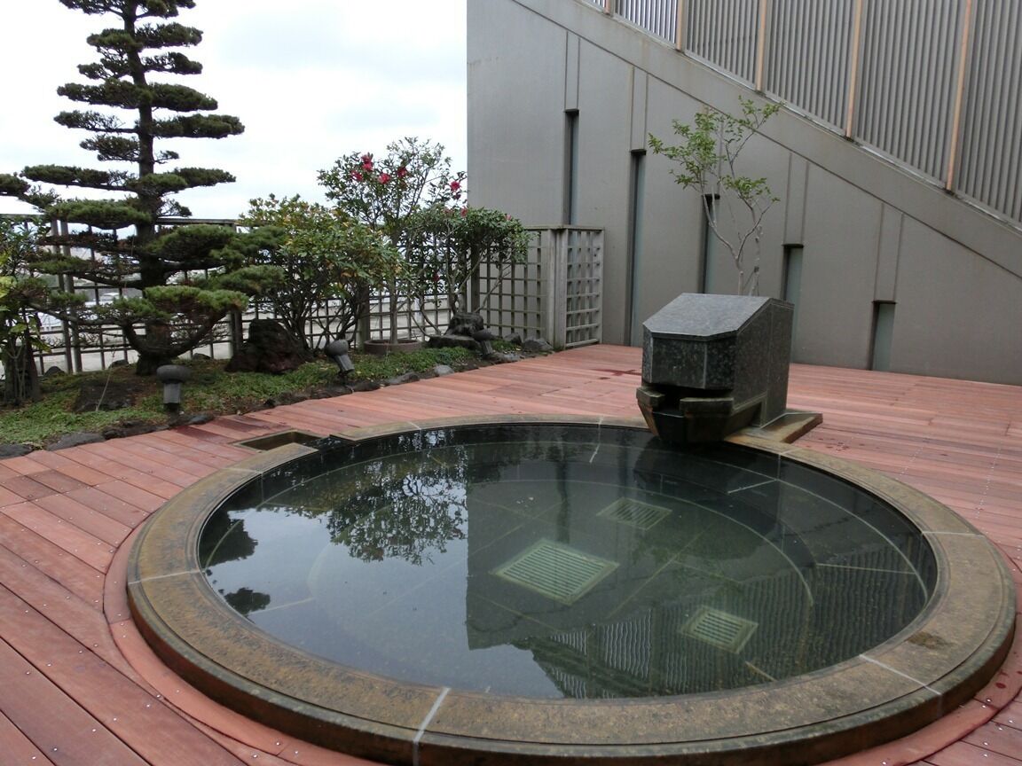 A circular hot spring with a stone structure in the center, surrounded by a wooden deck.