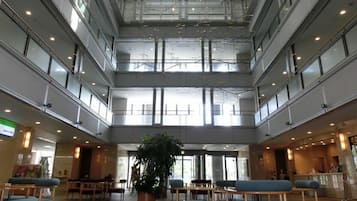A multi-level atrium with seating areas, a reception desk, and a large potted plant.