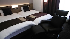 A hotel room with two beds, a desk, and a chair. - Natural Hotspring Hotel Jichikaikan (Kagoshima)