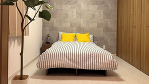 A bedroom with a bed, a potted plant, a nightstand, and a wardrobe.