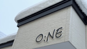 A building corner with a textured facade and the letters 'O:NE' prominently displayed.