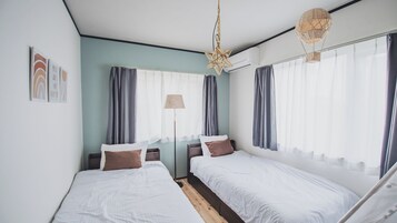Habitación de hotel con dos camas individuales, una lámpara de pie y una lámpara colgante con forma de estrella.