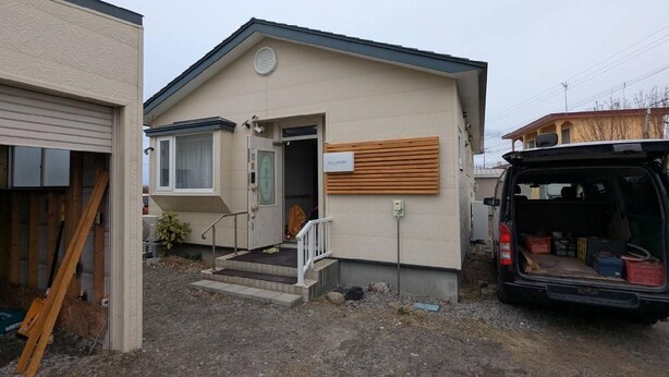 A small, single-story building with a front door, a small porch, and a vehicle parked in the driveway. - Akiyato Date Dream Date Home (Date)