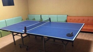 A ping pong table in a room with a green couch and an orange couch.
