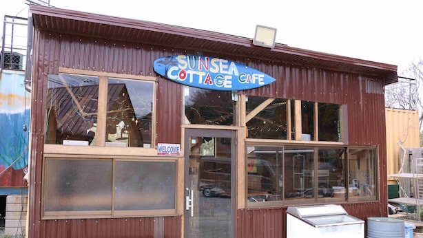 A rustic building with a large sign reading 'SUNSEA COTTAGE CAFE.'