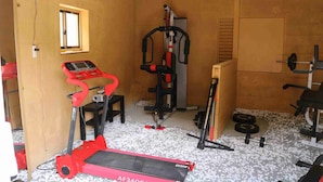 A gym with a treadmill, weight bench, and various exercise equipment.