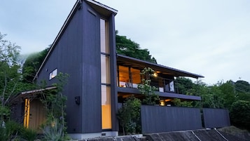 Una casa moderna de dos pisos con un balcón grande y techo plano.