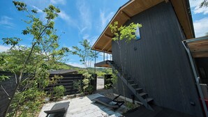 A modern building with a wooden exterior, a staircase, and a patio area with outdoor furniture.
