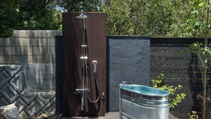 A metal water tank with a hose attached, positioned next to a wooden structure with a showerhead. - Manomano (Sumoto)