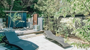 A backyard with two lounge chairs, a small shed, and a stone wall.
