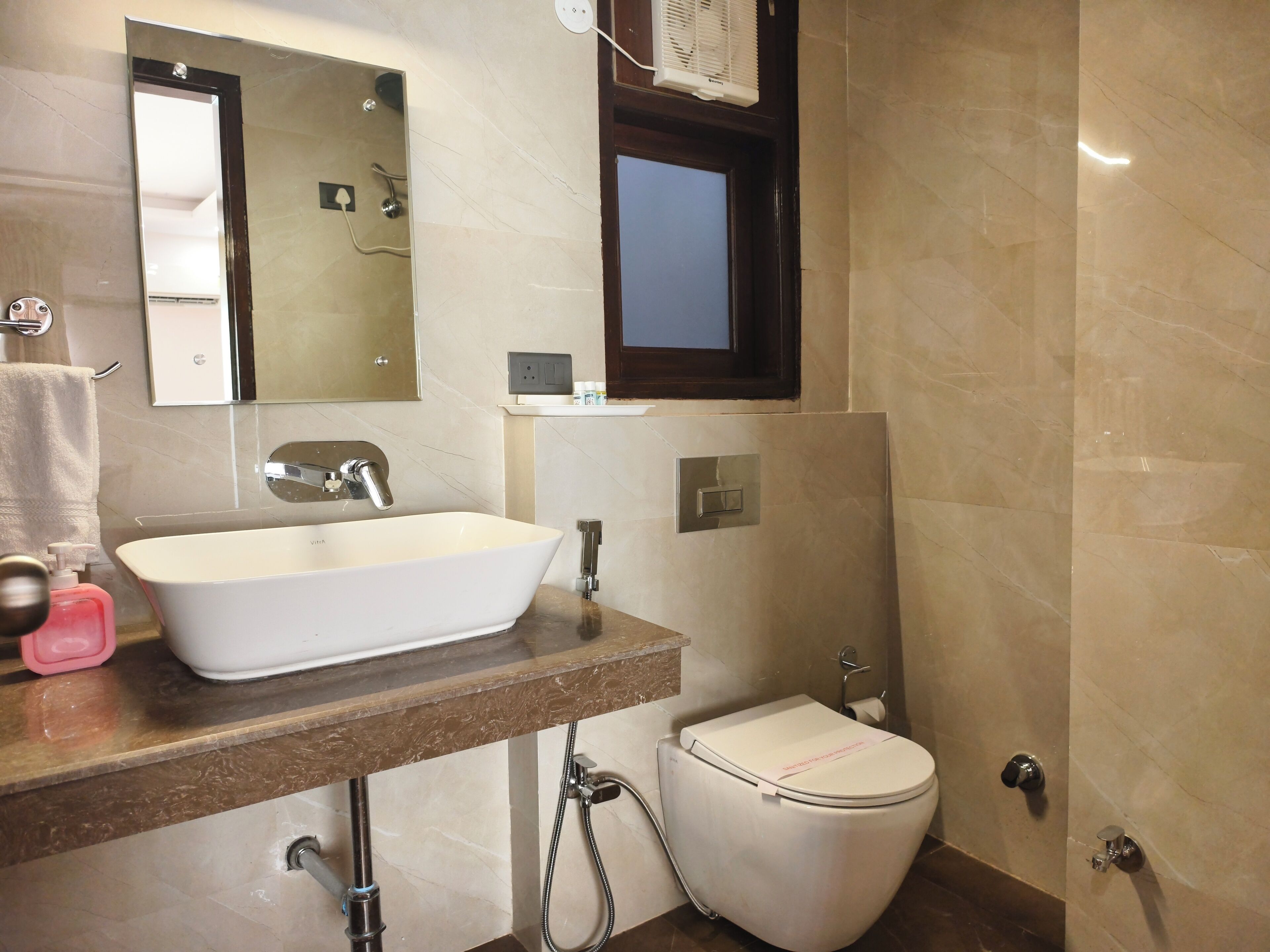 A bathroom with a white sink, a toilet, a mirror, and a shower.