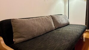 A sofa with two cushions, a lamp, and a wall with a curtain. - AJ Villa (Atami)