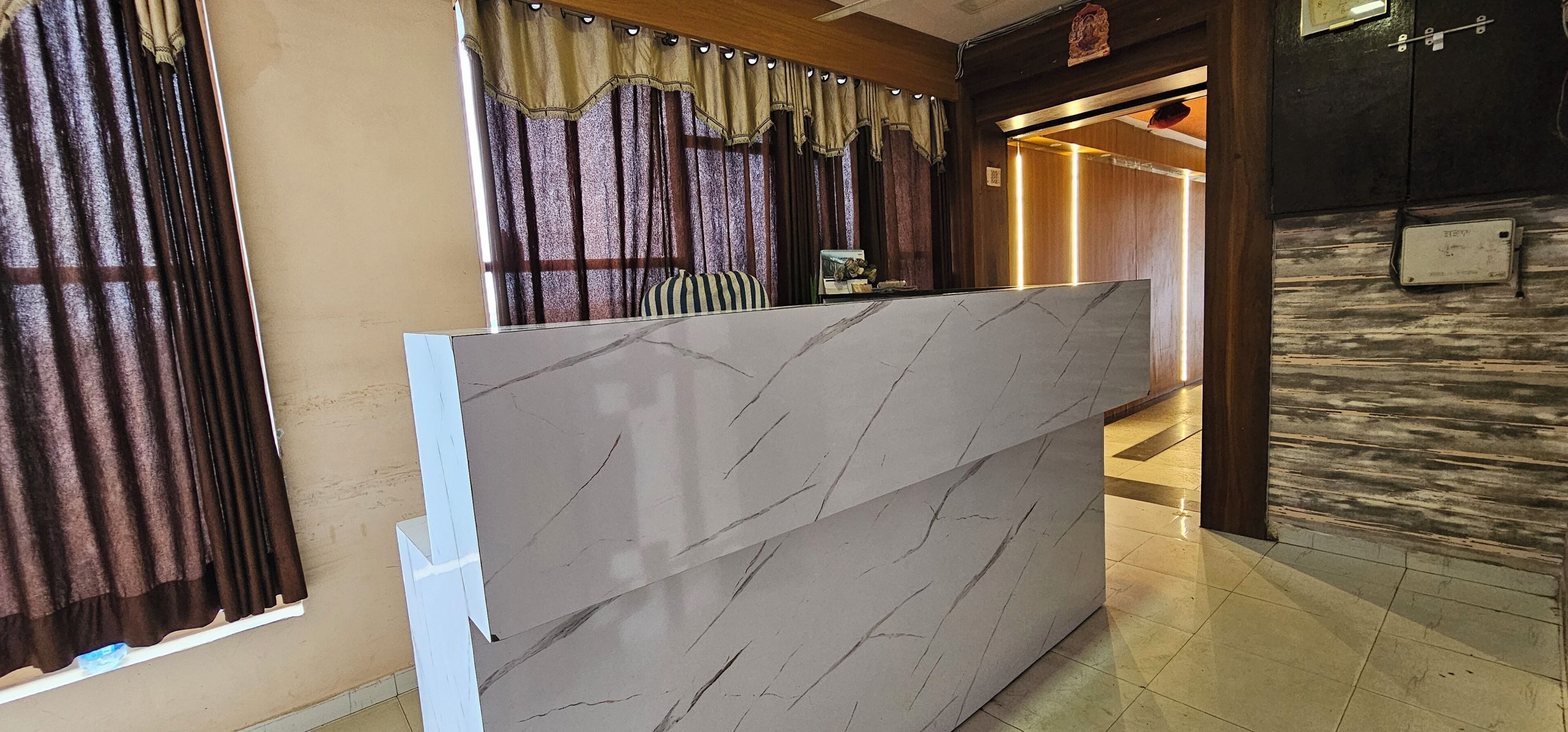 Un mostrador de recepción con diseño de mármol, una puerta de madera y un suelo de baldosas.