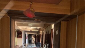 Eine Hotelhalle mit einer Rezeption, einer roten Deckenleuchte und einem gefliesten Boden.