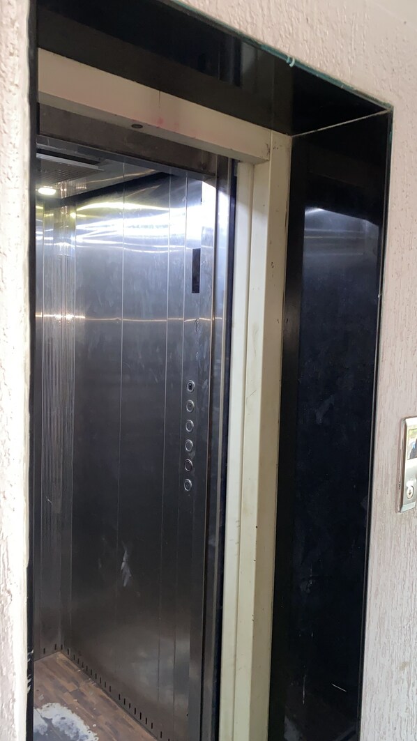 An elevator with metallic walls and a control panel with buttons. - Hotel Anand Palace Inn (Ahmedabad)