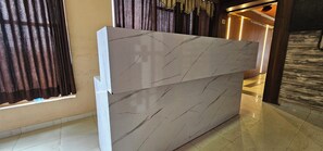 A reception desk with a marble finish and a modern design. - Hotel Anand Palace Inn (Ahmedabad)