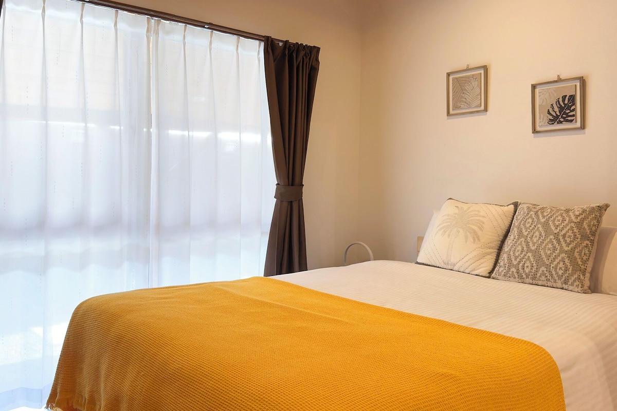 A hotel room with a bed, curtains, and two framed pictures on the wall.