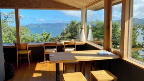 Habitació amb sostre de fusta, finestres amples, taula de fusta i cadires.