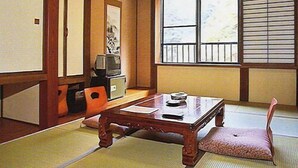 A traditional Japanese room with tatami flooring, a low wooden table, a television, and a sliding door. - Masugataya (Yonezawa)