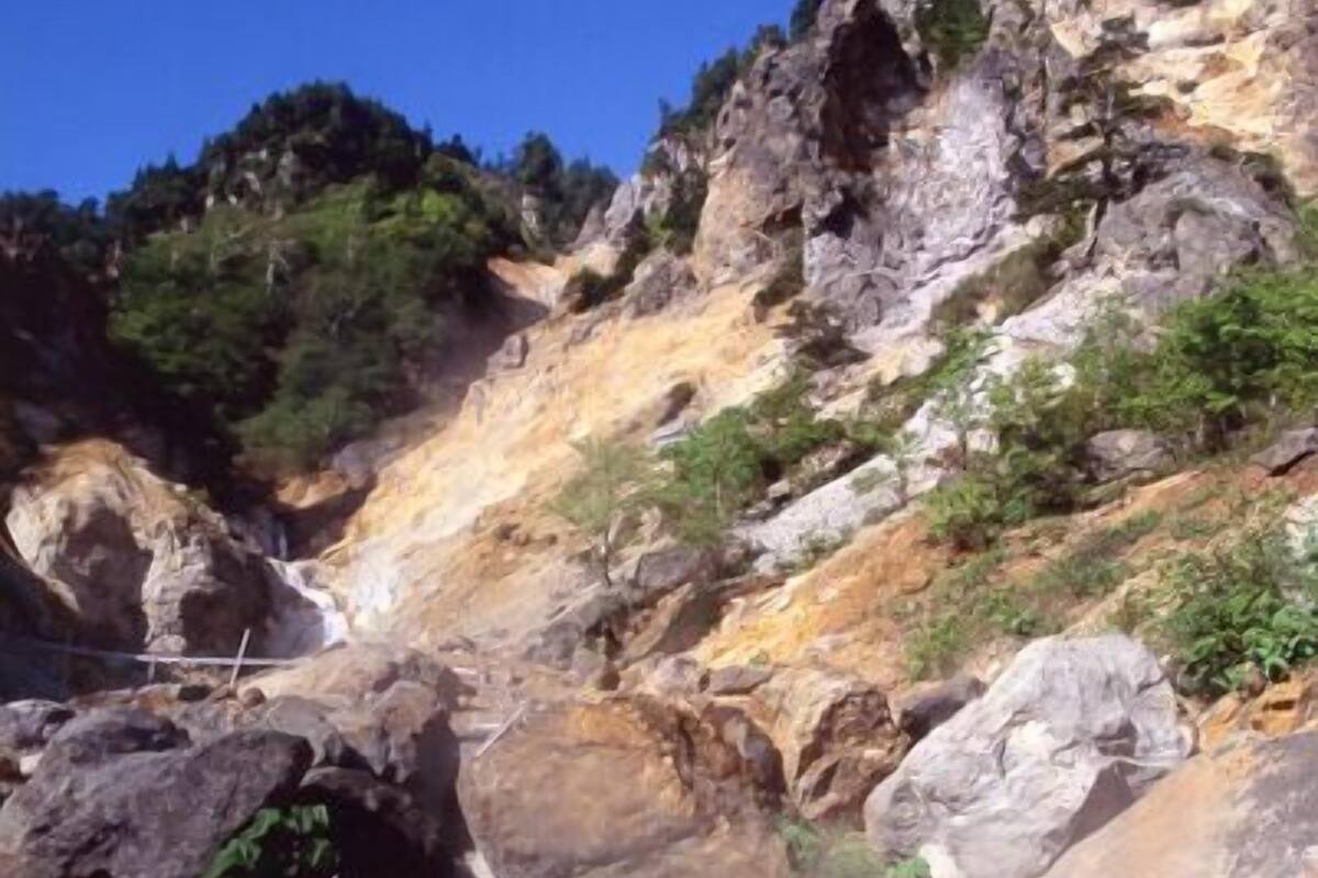 A natural landscape with a rocky terrain, a clear stream, and lush greenery.