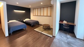 Una habitación de hotel moderna con dos camas, una mesita pequeña redonda, un escritorio con una silla y un ventanal con vistas.
