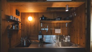 Cocina compacta con paredes de madera, un lavamanos central y diversos utensilios y electrodomésticos.