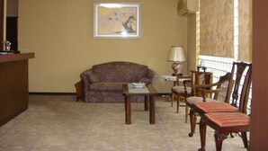 A room with a sofa, a table, and chairs, a framed picture on the wall, and a window with blinds. - Ikaho Bekkan (Nagano)