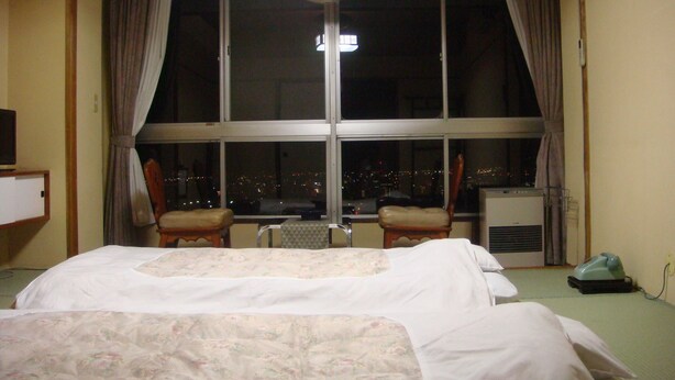A hotel room with a large window, a bed, two chairs, and a heater. - Ikaho Bekkan (Nagano)