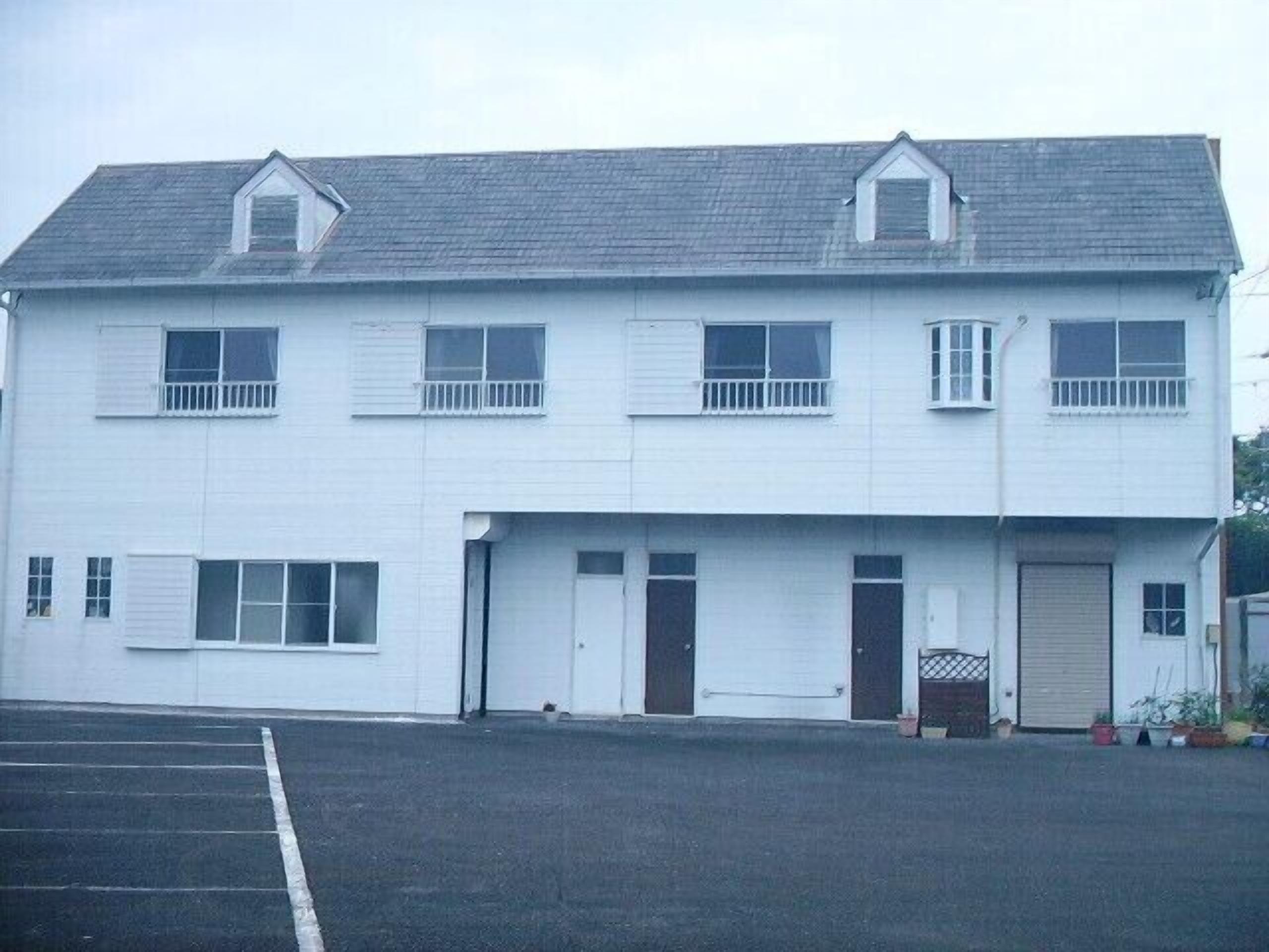 Un bâtiment à deux étages, doté d’un toit plat, de nombreuses fenêtres et d’une porte de garage.