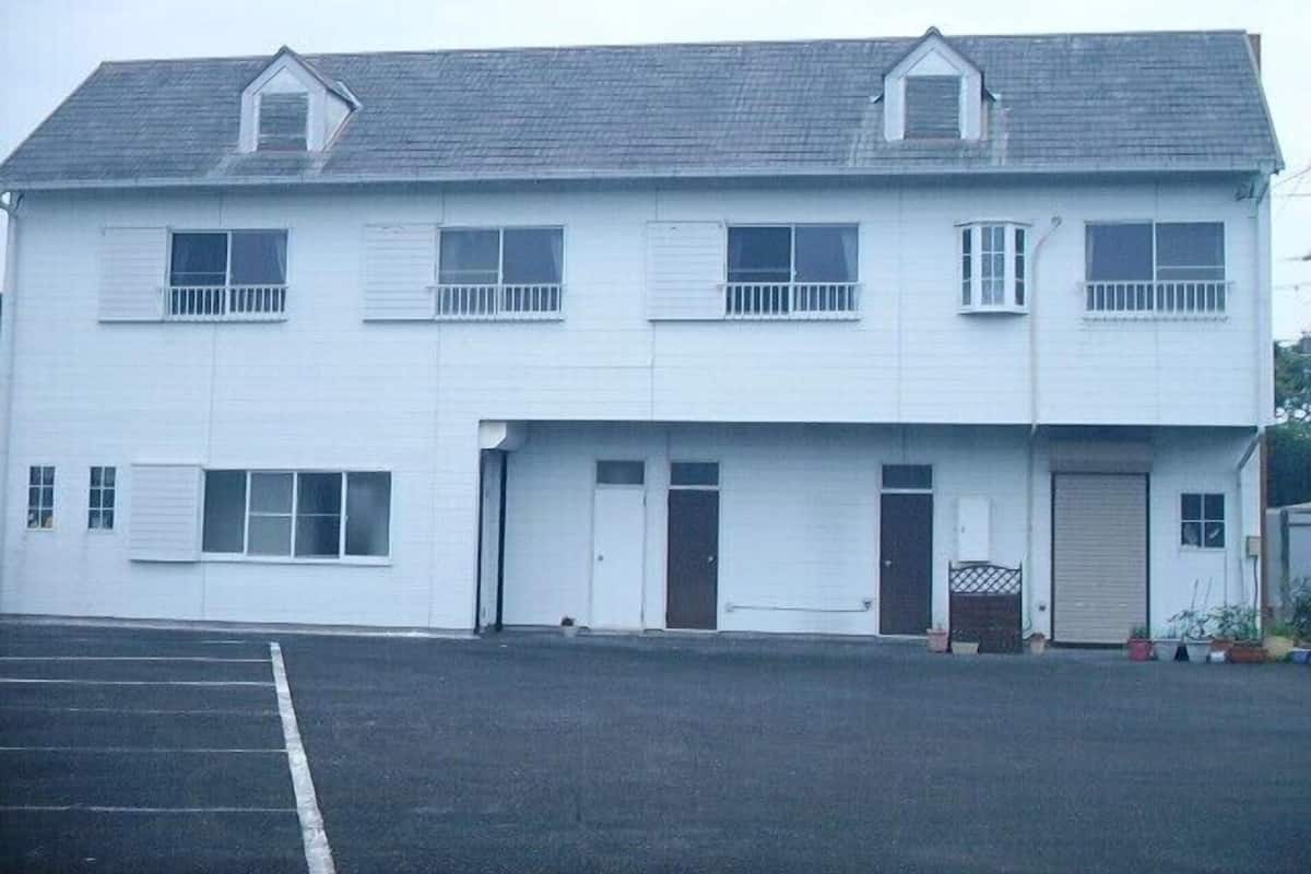 Un edificio de dos pisos con techo plano, múltiples ventanas y una puerta de garaje.