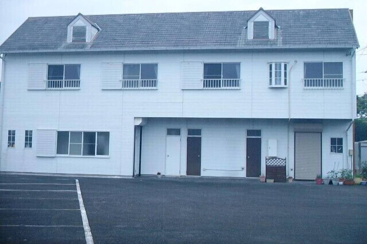 A two-story building with a flat roof, multiple windows, and a garage door.