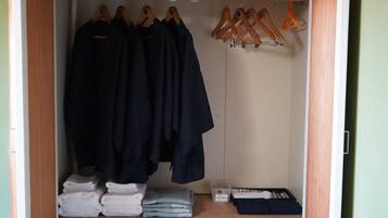 Un armario con ropa colgada, toallas dobladas y un caja de almacenamiento.
