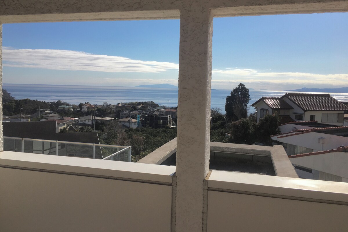 A view from a window overlooking a coastal town with houses and a clear sky.