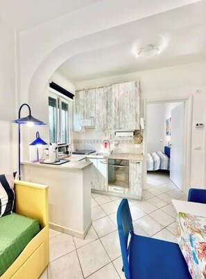 Un espace de vie compact comprenant une kitchenette, un coin repas et une chambre.